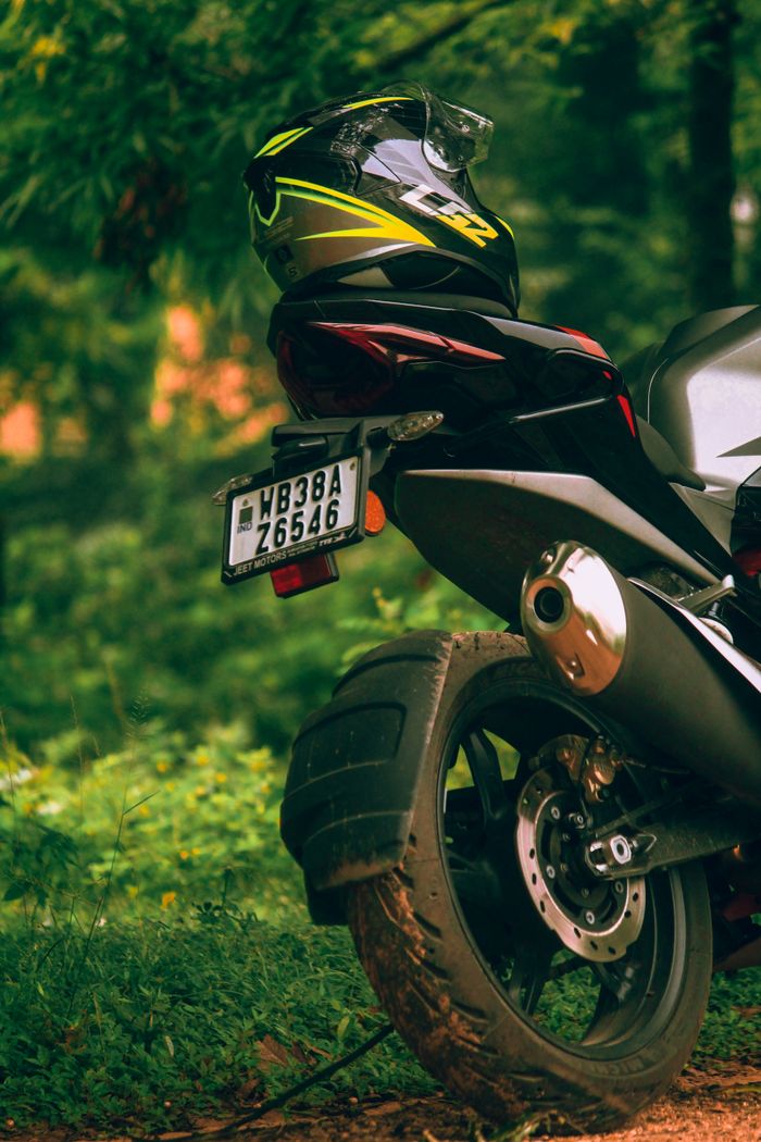 Close-up of a parked black motorcycle with a helmet in lush Sidabari, India.